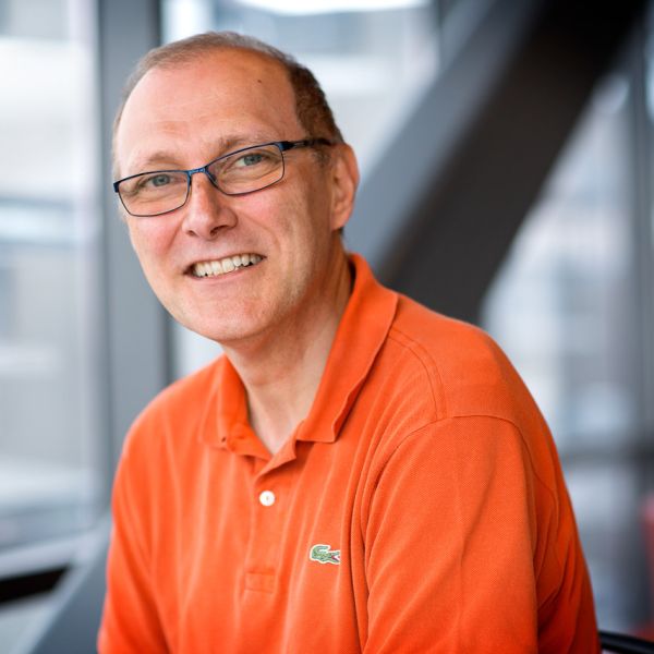 A color photo of a man sitting and smiling for a photo