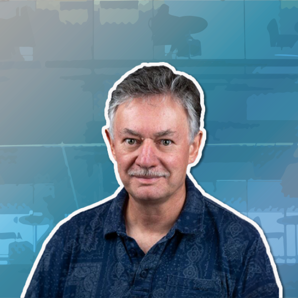 A color photo of a man smiling for a photo with a blue background