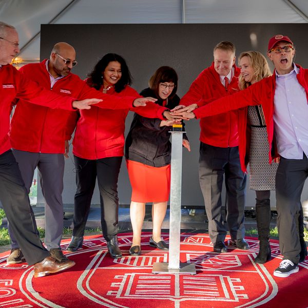 A color photo showing a group of people pressing a button