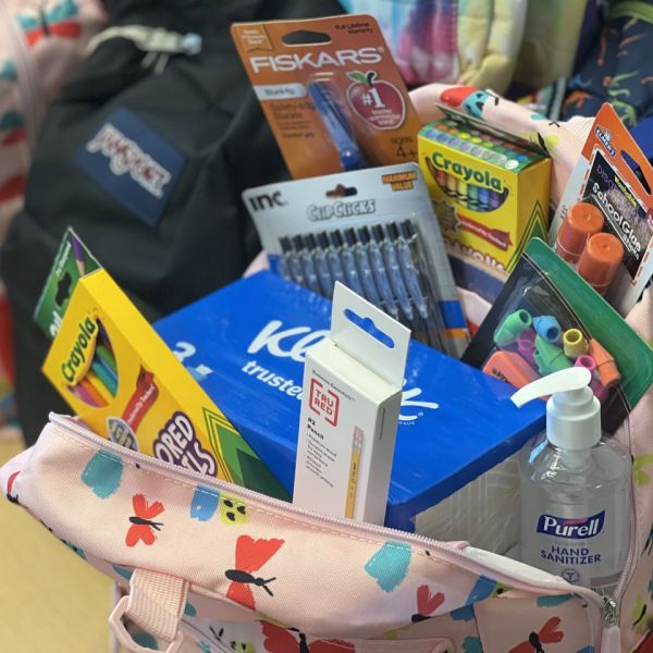 A color photo showing an open bookbag with school supplies inside