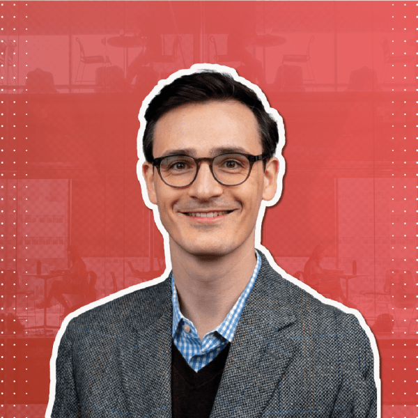 A color photo of a man smiling for a photo with a red and white background