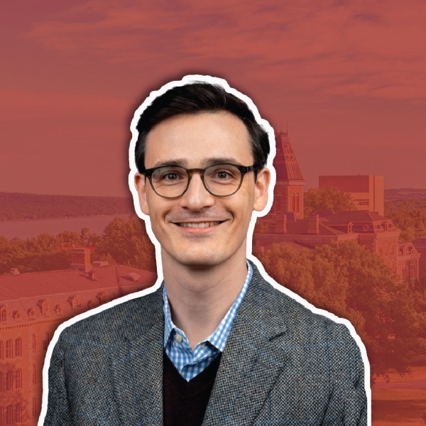 A color photo of a man smiling for a photo with a red background