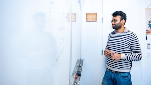 Eshan Chattopadhyay, assistant professor of computer science A color photo of a man working on a dry-erase board