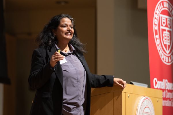 A color photo of a woman speaking in an auditorium