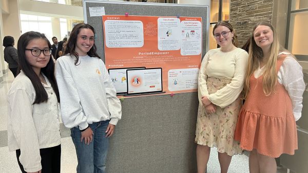A color photo of four women standing in front of a project display
