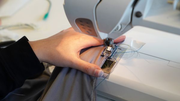 Photos by Louis DiPietro/Provided - Yu uses a home sewing machine to couch the conductive threads into the seams. Photos by Louis DiPietro/Provided Yu uses a home sewing machine to couch the conductive threads into the seams.