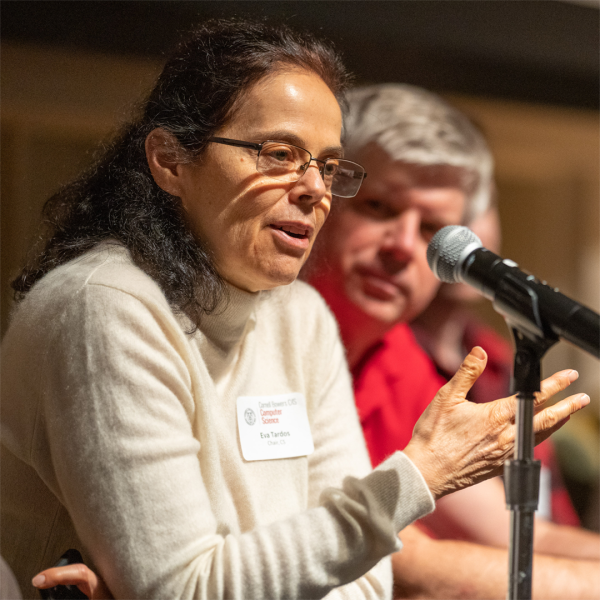 A color photo of a woman speaking at a microphone