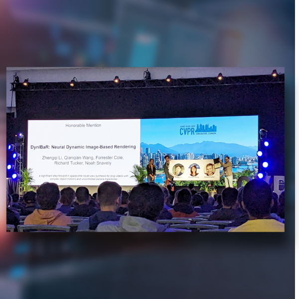 A color photo showing people on stage receiving an award in front of a large digital screen