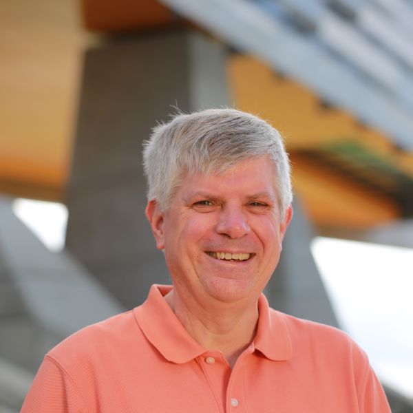 Man looking at camera in front of Gates Hall