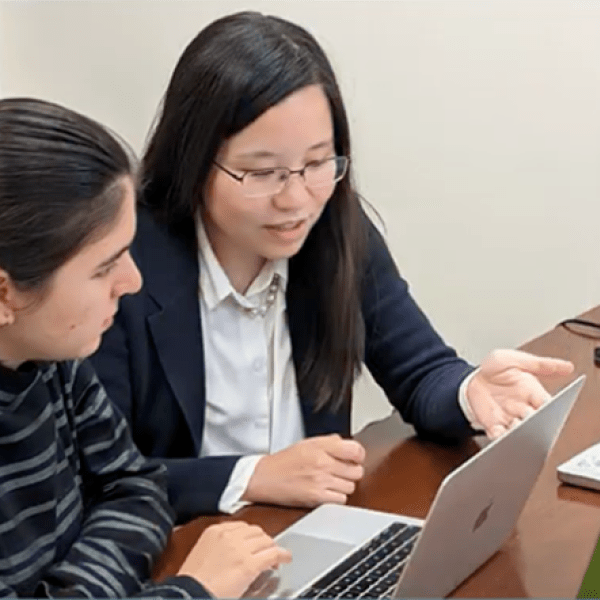 A color photo of two women working on a computer