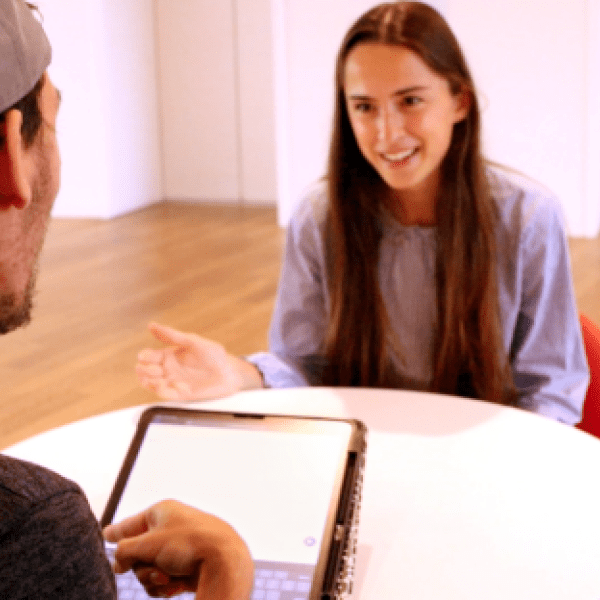 A color photo showing a man and a woman talking at a table. Provided
