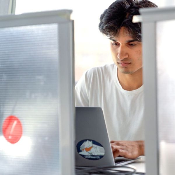 A color photo showing a man working on a computer